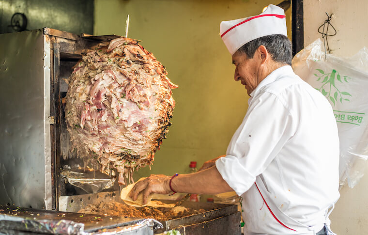 A vendor on our Mexico City taco tour cutting meat off a spit